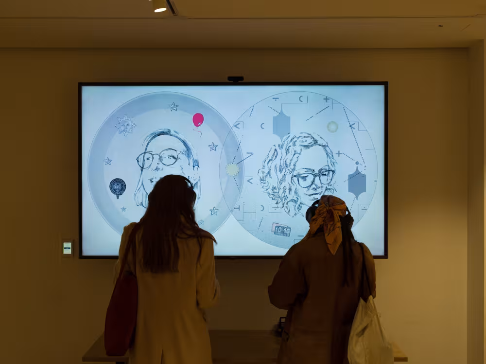 Artwork displayed on a screen with two people watching in front.