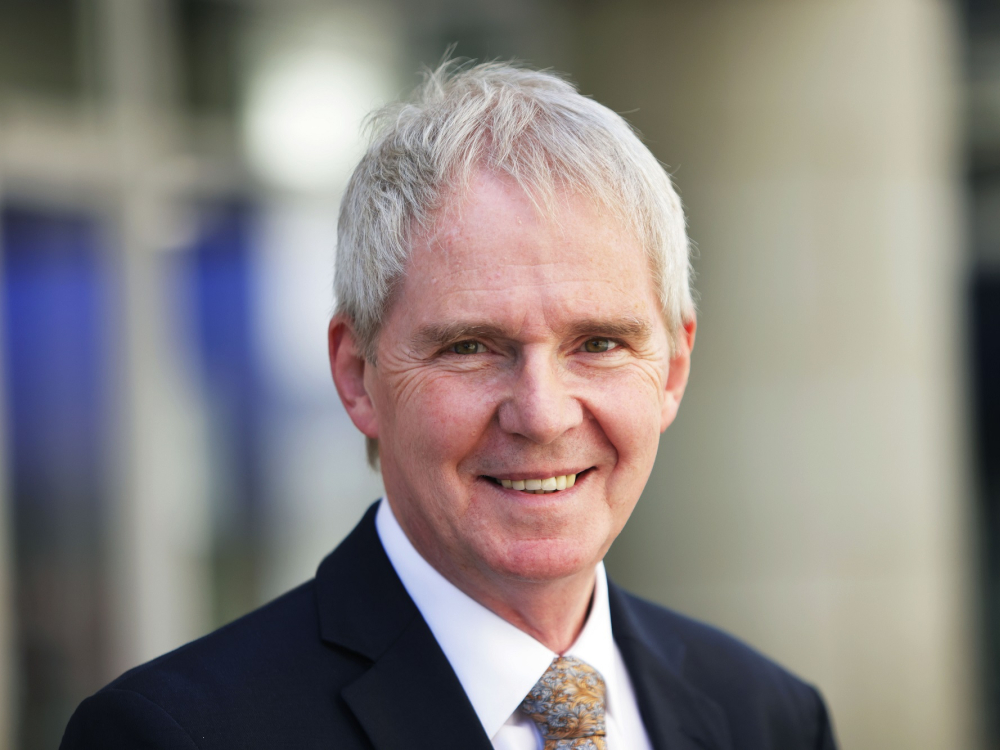 Man with grey hair smiles at camera