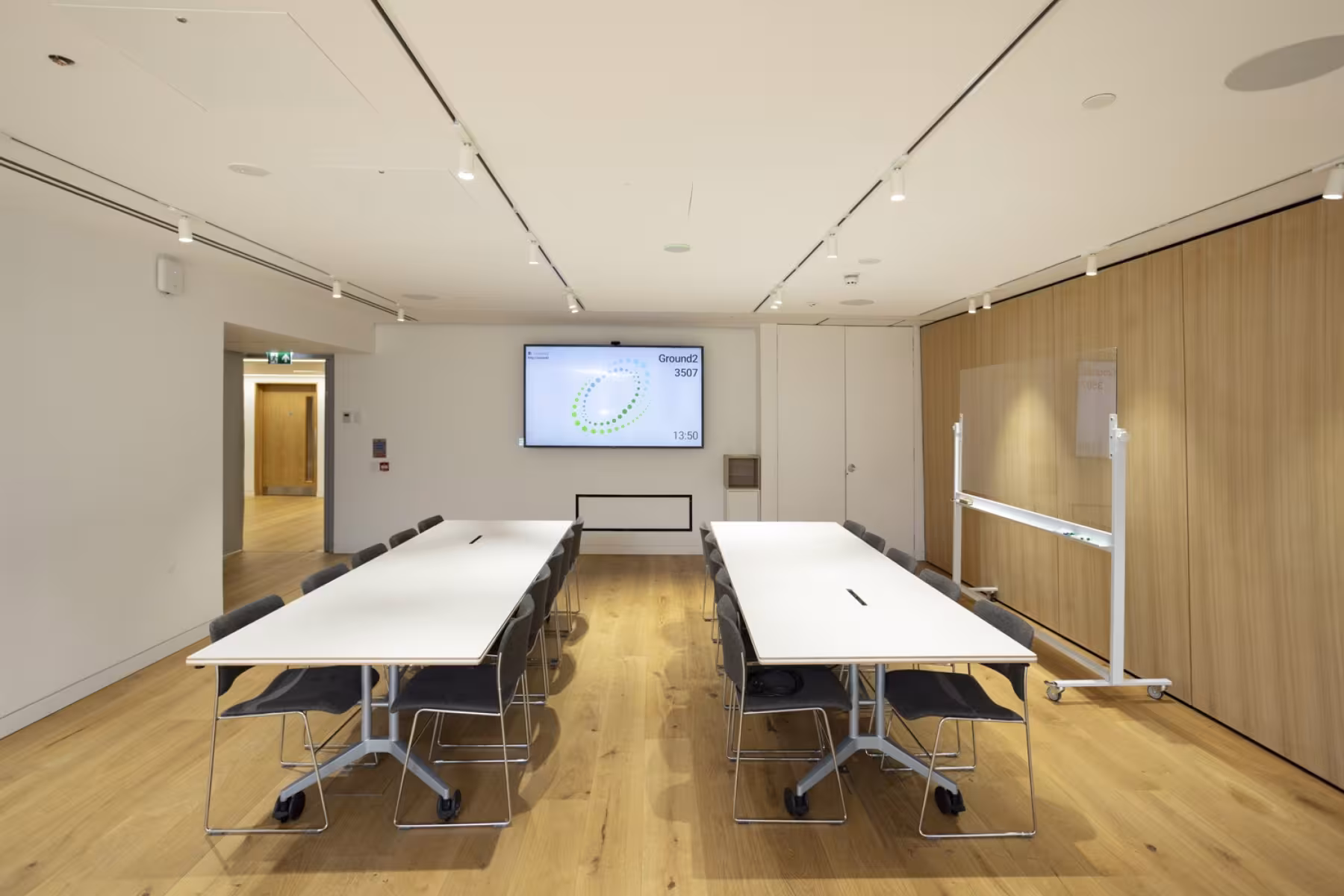 two long white tables in room with screen on wall