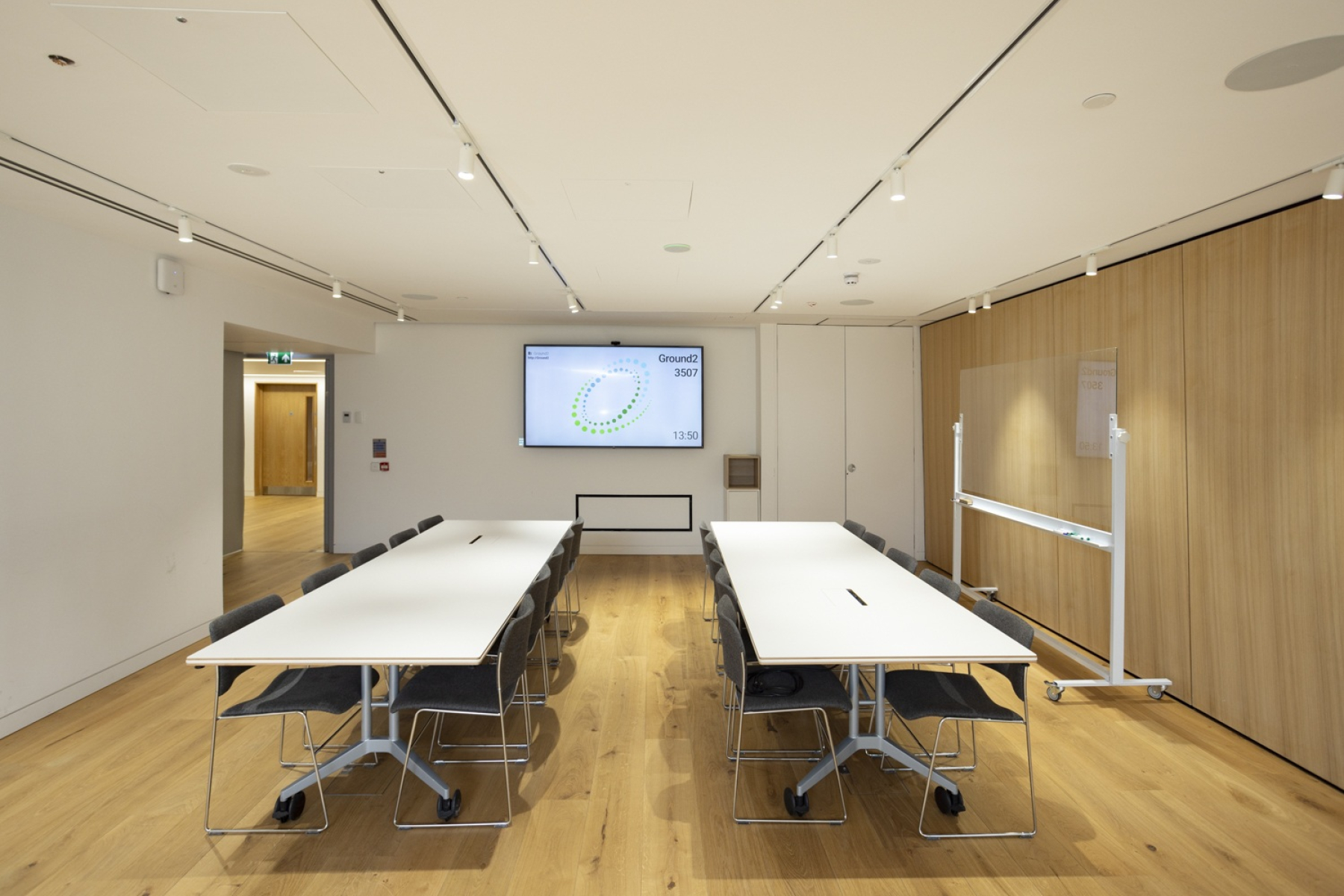 two long white tables in room with screen on wall